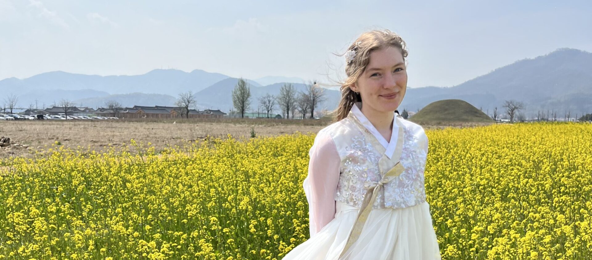 Girl wearing pink hanbok standing in a field of yellow flowers in South Korea — Nic-Nac Travel Pack